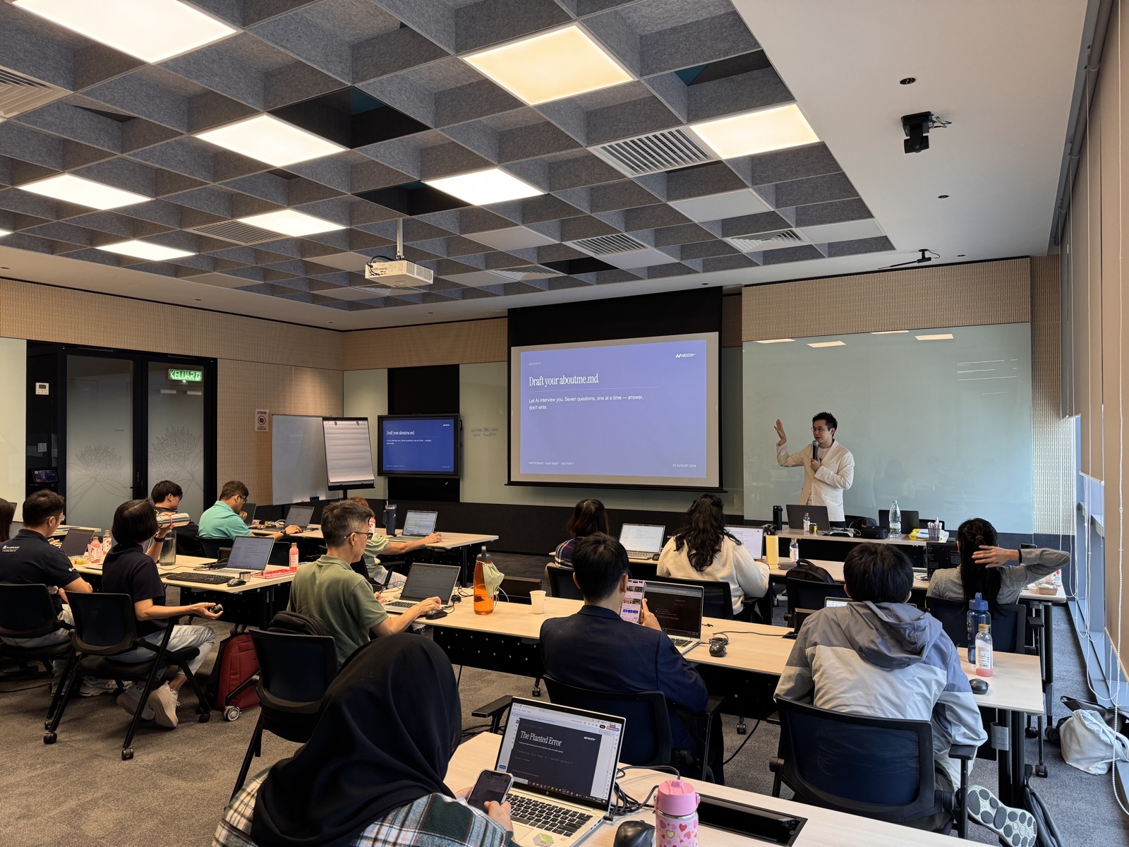 A Nexor AI trainer presenting to participants at laptops in a training room